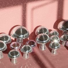 several shiny chrome knobs and covers on a pink surface with light shining through them