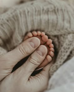 a person is holding their baby's foot in the middle of her hand,