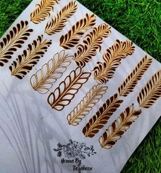 a sheet of paper with gold foil on it sitting in the middle of some grass