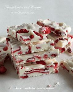 four pieces of white chocolate with strawberries and cream frosting stacked on top of each other