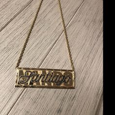 a gold necklace with the word knitting hanging from it's chain on a wooden surface