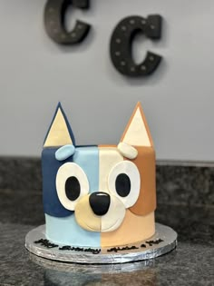 a cake with a dog design on it sitting on a table next to the letters c and c