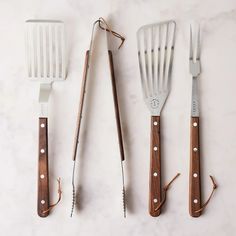 four kitchen utensils lined up next to each other on a white counter top