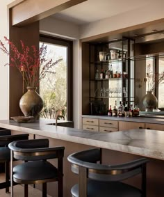 a bar with stools and bottles on the counter in front of large glass windows