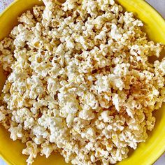 a yellow bowl filled with popcorn on top of a table