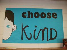 a blue sign that says choose kind on it next to a book shelf with books