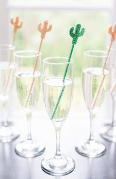 four wine glasses with straws in them sitting on a table