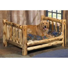 a dog laying in a bed made out of logs and wood with a blanket on it's side