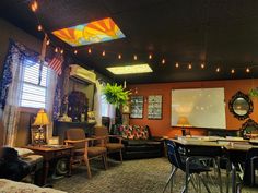 a living room filled with lots of furniture and lights hanging from the ceiling above it