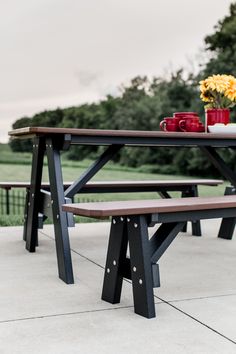 a picnic table with two benches next to it and flowers in the vase on top