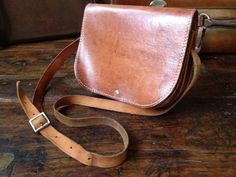 "Vintage Brown Leather Messenger Saddle Bag Handcrafted Vintage Heavy thick saddle leather, silver buckle closure with leather strap, adjustable shoulder strap. Color is a very lovely cinnamon brown with a rich heavy patina. White stitch detail. 2 interior compartments separated by a piece of leather. No lining. Measures; 9\" length, 7\" height, approx. 3.5\" depth, strap drop is 21\" at longest length and is adjustable. Wonderfully aged to perfection, this bag has an awesome patina only years o Cognac Saddle Bag With Leather Lining, Brown Leather-lined Saddle Bag, Classic Leather Strap Crossbody Saddle Bag, Leather Handle Saddle Bag, Classic Brown Saddle Bag, Brown Leather-backed Saddle Bag, Crossbody Saddle Bag, Cinnamon Brown, Aged To Perfection