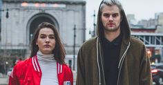 a man and woman standing next to each other on the street in front of a building