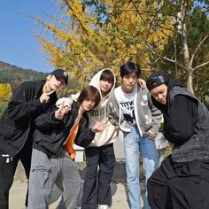 group of young men standing next to each other in front of trees and rocks with yellow leaves on them