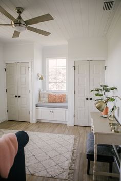 a living room with white walls and wood flooring, a window seat on the far wall