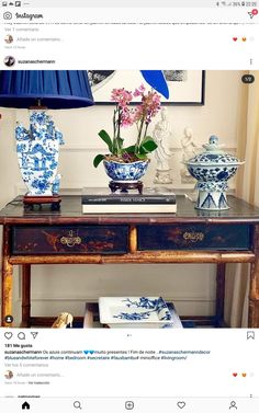 a table with vases and flowers on it in front of a blue lampshade