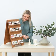 a woman standing next to a wooden table holding a display board with pictures on it