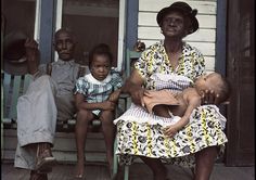 an older woman sitting on a porch with two young boys and a baby in her lap