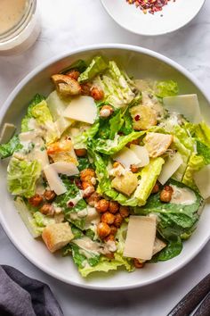 a white bowl filled with lettuce, cheese and other food on top of a table