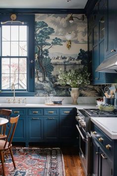 a kitchen with blue cabinets and a painting on the wall behind the stove top oven