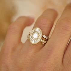 a woman's hand holding a ring with an oval shaped diamond in the center