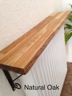 a wooden shelf sitting on top of a white radiator next to a potted plant