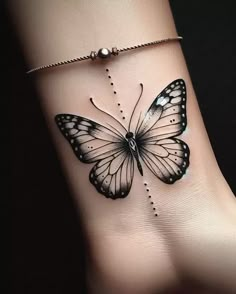 a black and white butterfly tattoo on the side of a woman's foot,