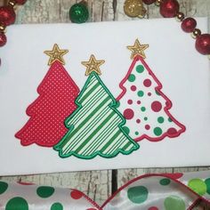 two christmas trees on a white board with red and green ribbons around it, next to a polka dot bow