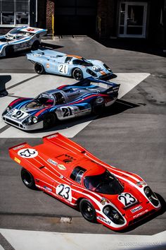 three race cars are lined up in a parking lot