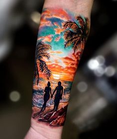 a man with a tattoo on his arm holding the hand of a woman at sunset