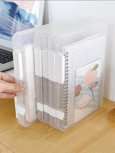 a person holding a clear plastic folder with pictures on it and a laptop in the background