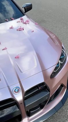 a pink sports car is parked on the side of the road with flowers all over it