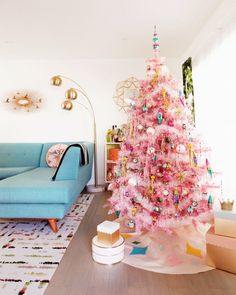 a pink christmas tree is in the middle of a living room with blue couches