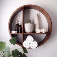 a wooden shelf with towels and vases on it next to a potted plant