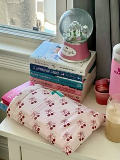 a stack of books sitting on top of a table next to a cup and lamp