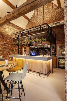 an industrial style bar and dining room with exposed brick walls, wood beams, and modern chairs