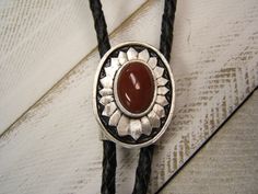 Complete your look with this Southwestern, Western, Pewter Antiqued Sunburst Bolo Tie. The Handmade, Unique Design will make you Standout everywhere..,  - Minimalist Southwestern Concho Bolo Tie,  - Pewter Antiqued, Anti-Tarnish Added for Lasting Beauty. - Genuine Carnelian Cabochon, - 30 TO 42 inch, Genuine Black, Light Brown or Dark Brown Leather Cord, - Silver Tone Cord End Tips,  - "NEW" Tension Bolo Back,  which is easier to use and helps the cord to keep from fraying. - Concho is Approx. 1 Carnelian Stone, Minimalist Gifts, Bolo Tie, Dark Brown Leather, Lariat Necklace, Gift For Men, Wedding Necklace, Gifts For Husband, Leather Cord