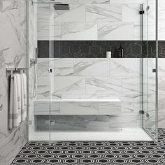 a bathroom with black and white tile flooring and walls, along with a walk in shower