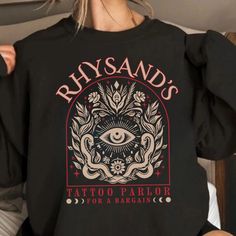 Rhysand's Tattoo Parlor Sweatshirt, Feyre And Rhysand Sweater, Acotar Velaris Hoodie, The Night Court, Acotar Fan Gift, Bookish Gift. 🚨 ATTENTION 🚨 📏 PLEASE REVIEW THE "SIZE CHART" IN THE IMAGES BEFORE ORDERING. 📏 🛒 HOW TO ORDER 🛒 1.🖼️ Please review all the photos carefully. 2.👕 Choose your t-shirt size and color. 3.✍️ Add any personalization or notes to the seller, if available. 4.🛒 Click "Add to Cart". You can return to add more shirts if needed. 5.🛍️ Click "Proceed to Checkout". 6.🚚 Select your preferred shipping option: USPS Standard Shipping, USPS Priority Mail, UPS 2nd Day Air, UPS Next Day Air. Please note that the shipping option cannot be changed after placing your order. 7.💬 During checkout, feel free to include any special requests in the notes to the seller section. Acotar Dust Jackets, Rhysand's Tattoo, Night Court Acotar, Acotar Velaris, The Night Court, Tattoo Parlor, Feyre And Rhysand, Night Court, Tattoo Parlors