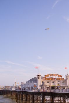 a pier with people walking on it and an airplane flying overhead