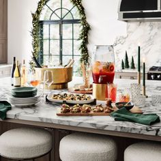 a kitchen counter topped with lots of food and wine glasses next to a stove top oven