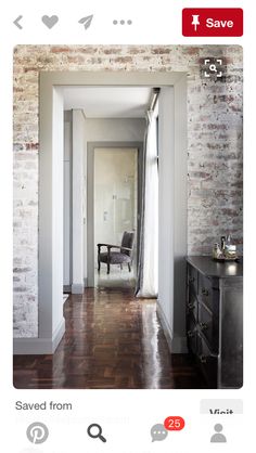 an empty room with brick walls and hardwood floors, along with a chair in the corner