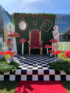 an outdoor stage set up for a party with red chairs and flamingos on it