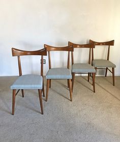 three wooden chairs sitting next to each other on carpeted floor in front of white wall