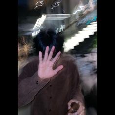 a blurry image of a man with his hand on his face and hands in the air