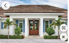 a house with blue shutters and palm trees on the front door is shown in this image