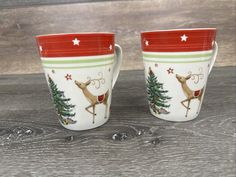 two christmas themed cups sitting on top of a wooden table next to eachother