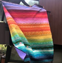 a woman is holding up a colorful quilt