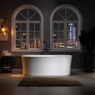 a bathtub sitting in front of two windows with city lights on the other side