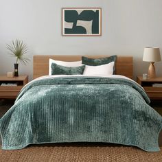 a bed with green bedspread and two nightstands in a bedroom next to each other