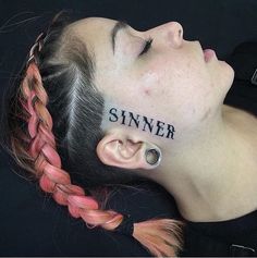 a woman with the word sinn written on her face and behind her ear is a pair of scissors